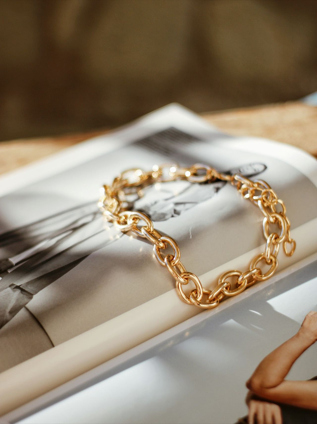 Bracelet à grosses mailles en or posé sur un magazine